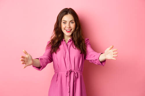 Portrait smiling young woman standing against pink background