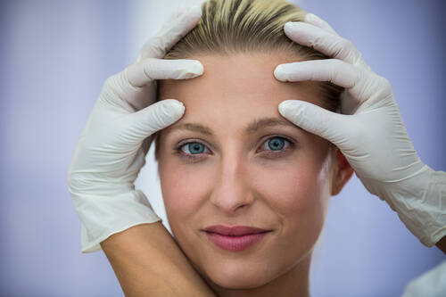 Doctor examining female patients face from cosmetic treatment (1)
