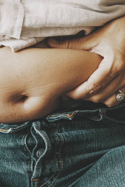 Close up female holding her belly with fat unhappy body positivity concept woman thinking about diet lazy lifestyle eating disorder unhealthy people overeating feed changes baby born
