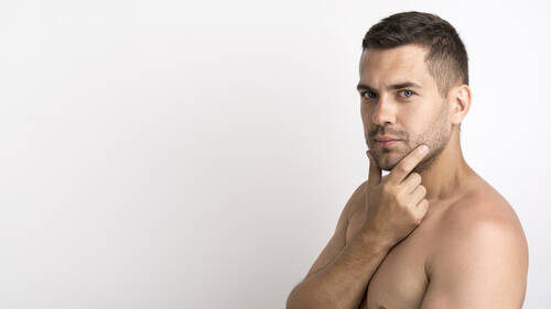 Shirtless young man posing against white background